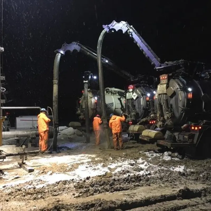 Vacuum trucks and a crew working a night job in the snow