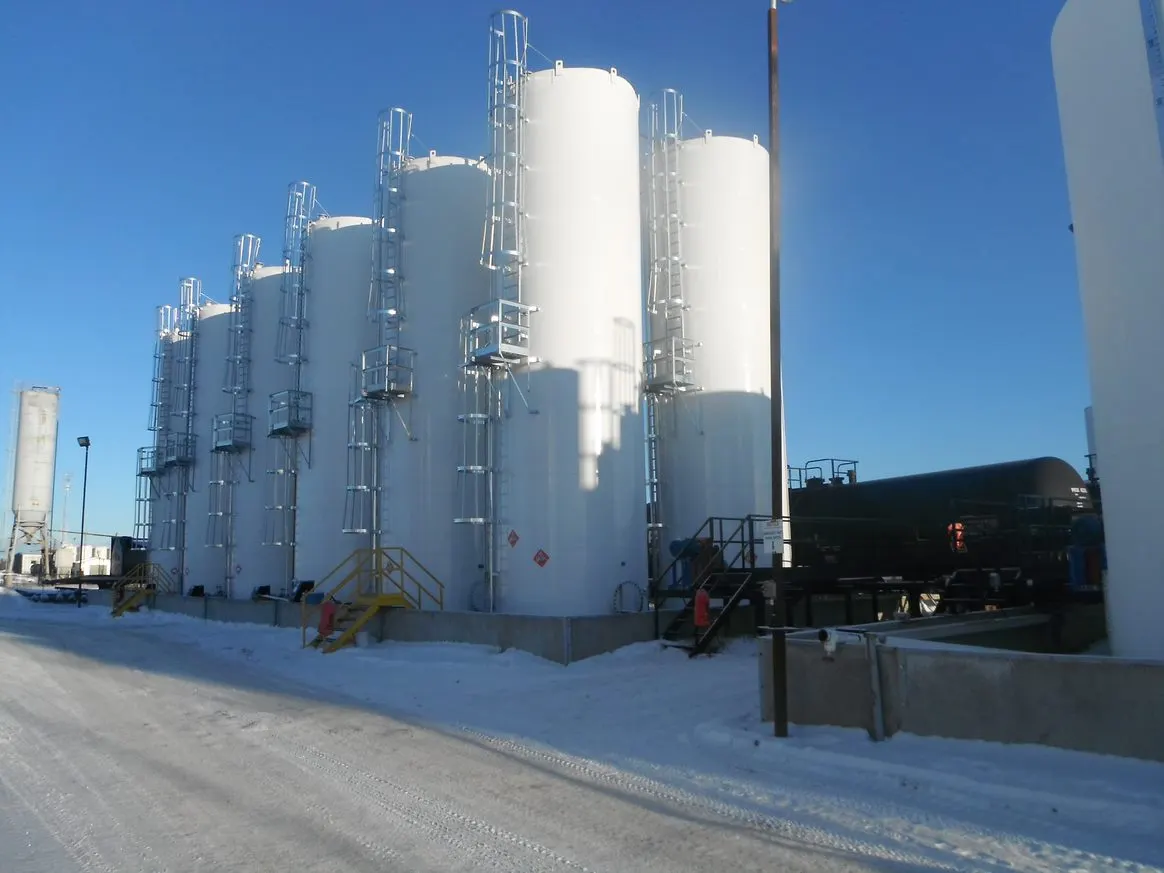 White storage tanks beside a rail tank car at a snowy terminal