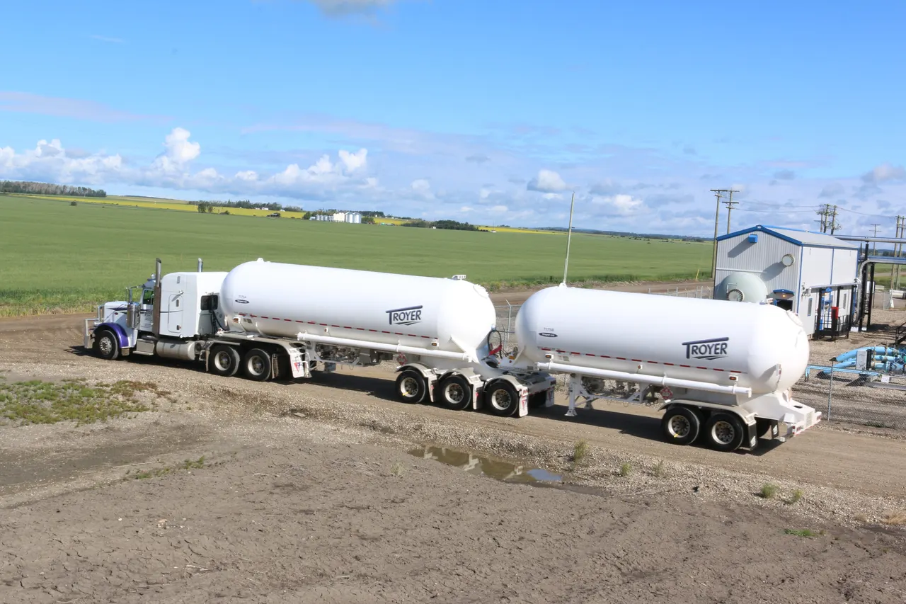 White tank trailers lettered TROYER at an oilfield site