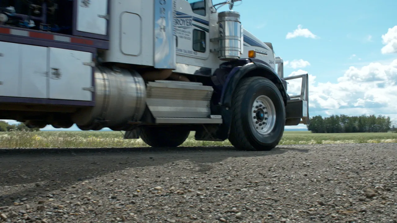 A Troyer truck on a gravel pad under a big prairie sky, a still from Troyer's 60-second video